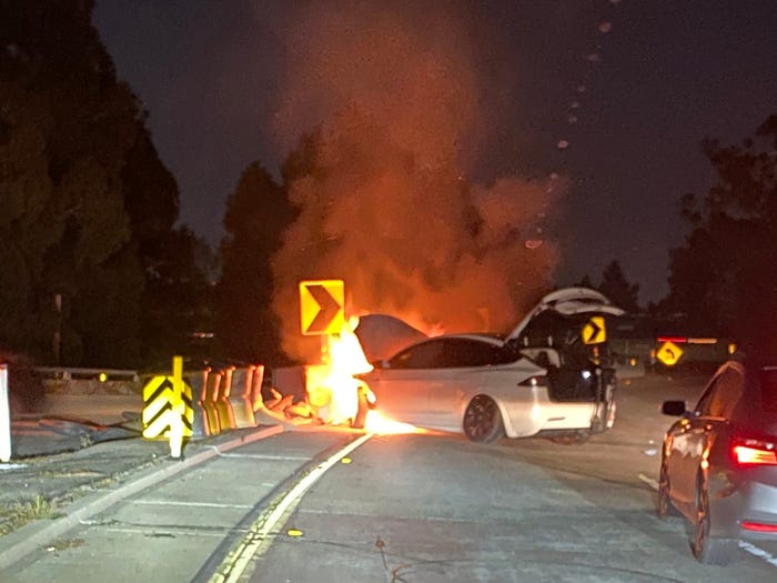 A picture showing a Tesla in flames after it crashed into a barrier.
