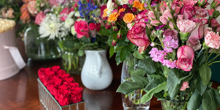 Several different kinds of flowers in vases on a wooden table