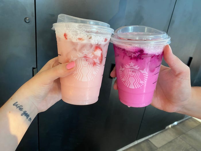 two people holding pink drink next to a dragonruit refresher at starbucks