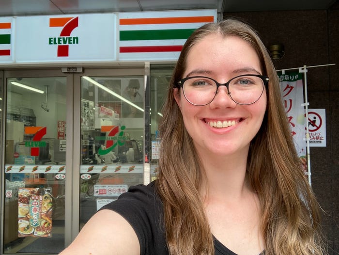 Author Sarah Vincent smiling in front of a 7-Eleven in Japan