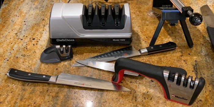 Four different knife sharpeners and 3 knives set on a granite countertop.