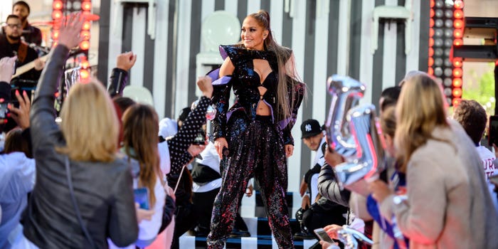 Jennifer Lopez performs on stage surrounded by audience members.