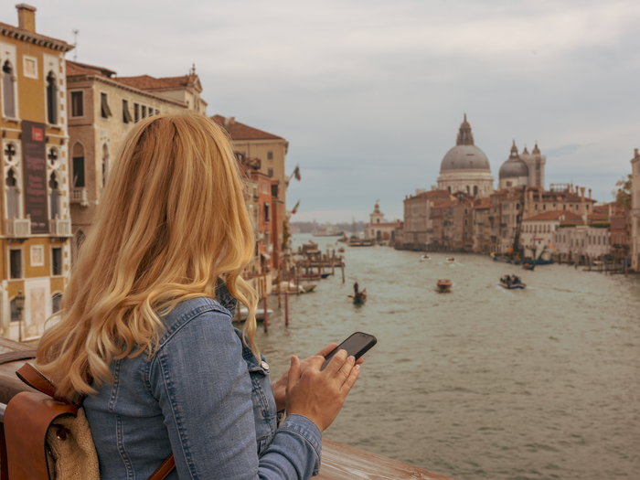 a woman looking at venice canals with her phone in hand