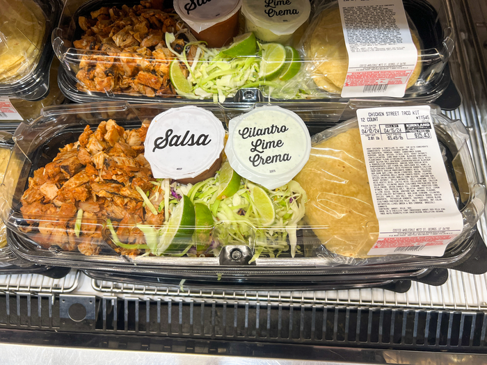 A premade salsa platter with chicken pieces, salsa, cilantro-lime crema, lime wedges and lettuce, and a package of tortillas