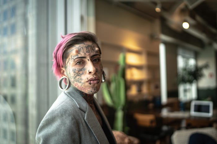 Woman in suit jacket with face tattoos