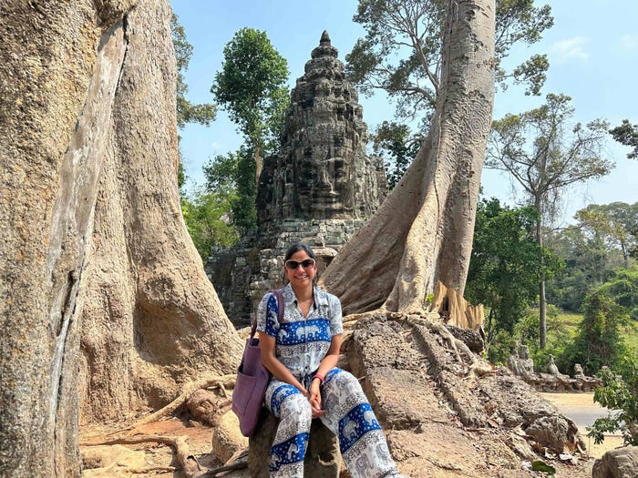 Woman sitting near trees in front of Angkor Wat in Siem Reap, Cambodia