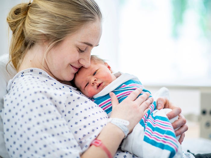 New mom holds her baby in hospital bed
