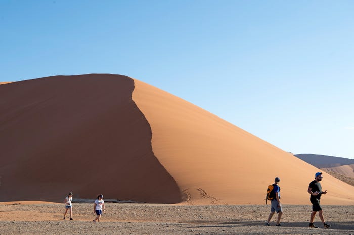Tourists walk by a dune at Namib-Naukluft National Park in Namibia in January 2022.