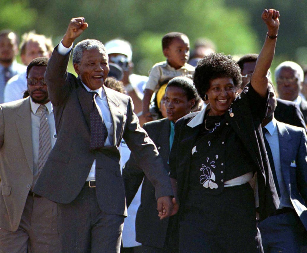 Nelson Mandela, walking alongside his wife, raises his fist in celebration of being released from prison.