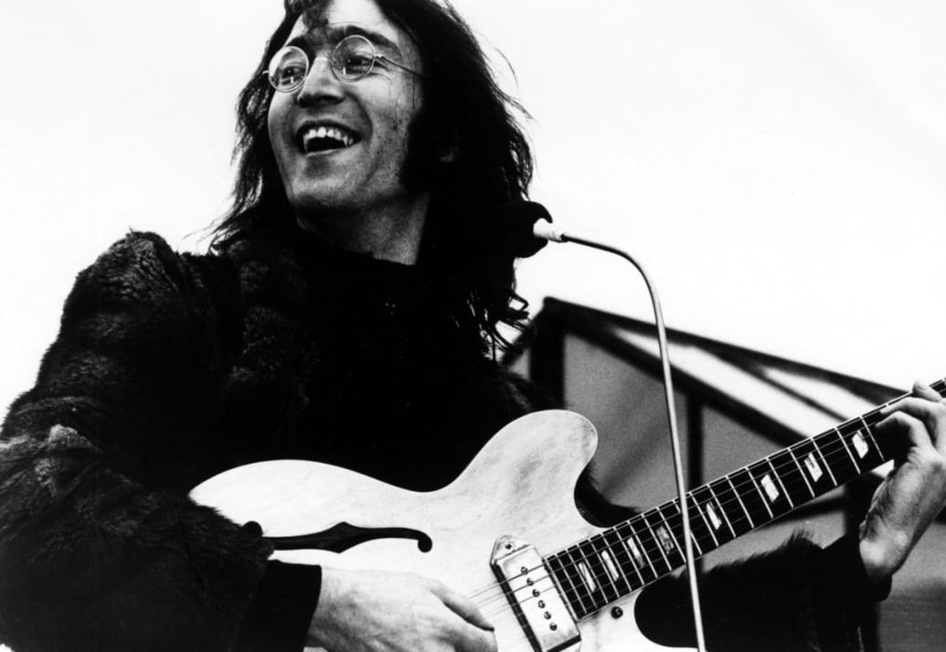 John Lennon plays the guitar in a still from ‘Let it Be’