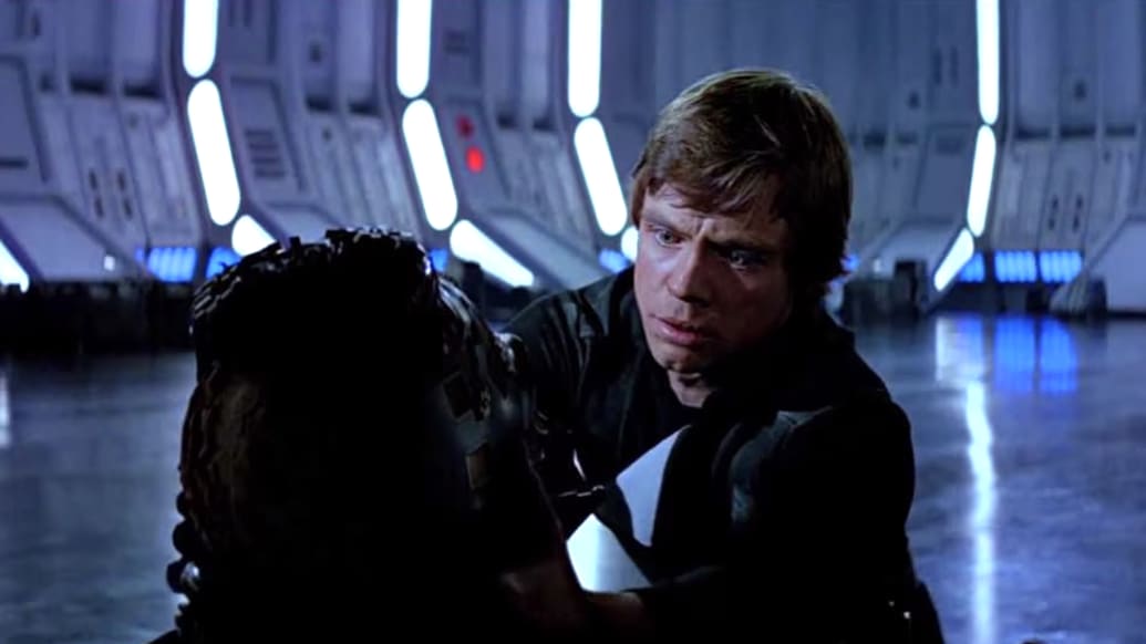 Photo still of Luke takes Anakin’s mask off at the end of Return of the Jedi