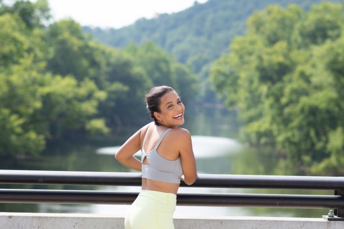 Pro dancer Madeline Collins is pictured posing in workout clothes on an outdoor walkway smiling at the camera