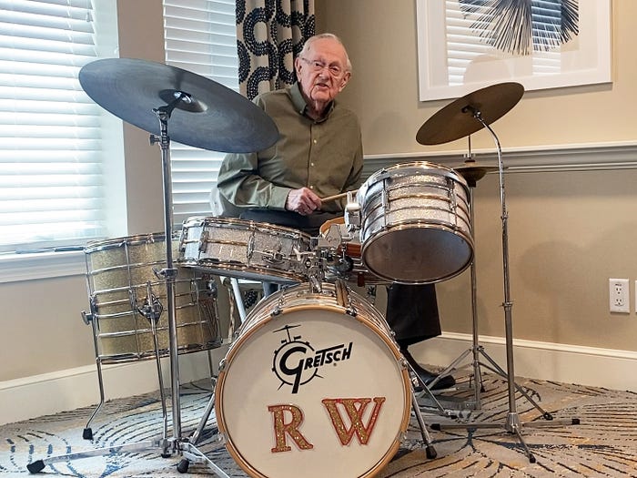 An older man playing on a drum kit