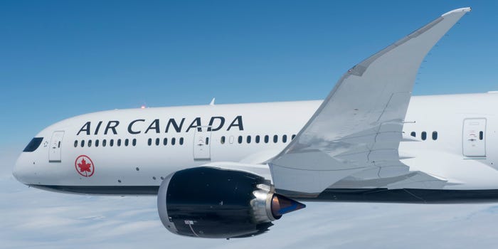 Side view of an Air Canada Boeing 787-9 in flight over a cloud layer.