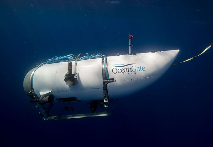 A side view of the Titan submersible, a large white cylindrical vessel with a rounded front with a small porthole, in water.