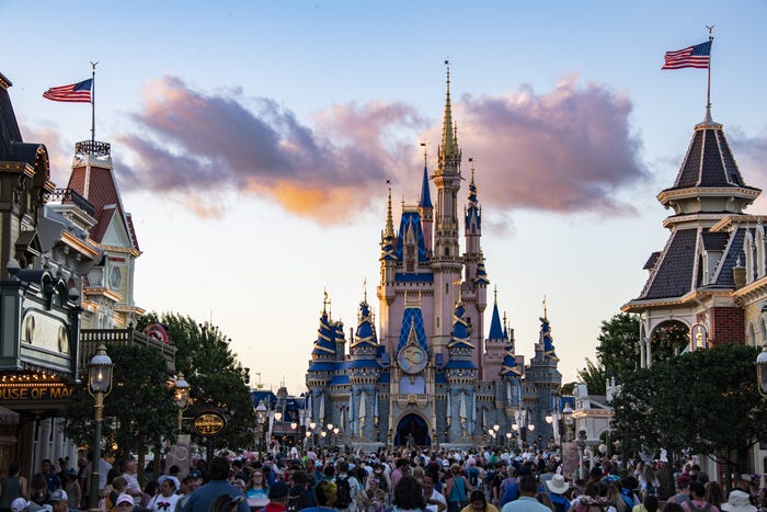 A large crowd walks towards a castle at Disney World in Orlando, Florida.