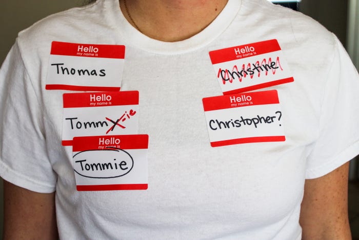 Person wearing white shirt with name tags bearing the name Thomas, Tommie, and Christopher.