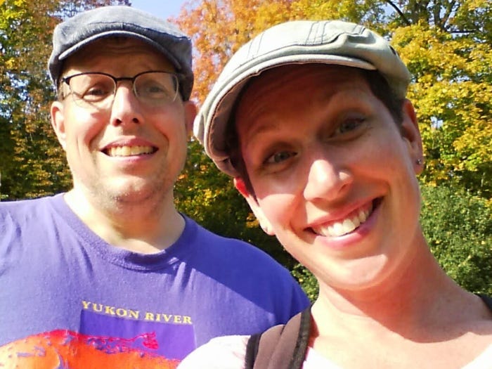 Couple wearing hats and standing in front of trees