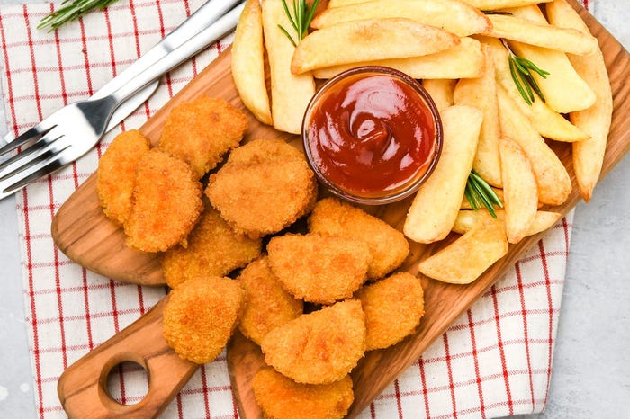 a board of chicken nuggets and french fries with ketchup
