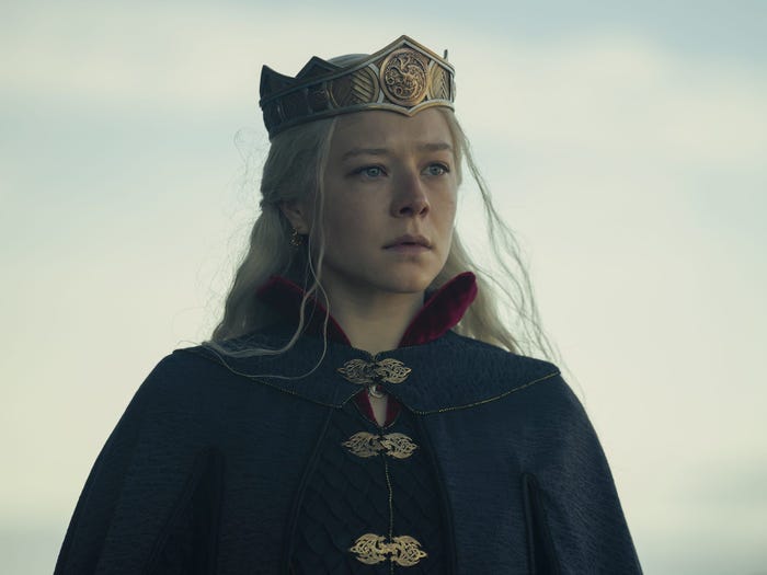 A woman in a black cape with a crown on her head.