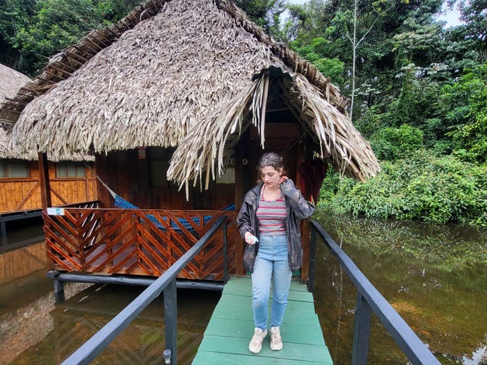 eibhlis posing in front of an overwater lodge in the amazon rainforest