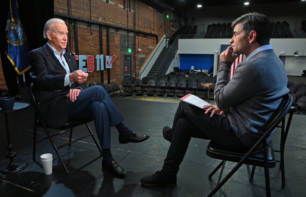 Joe Biden and George Stephanopoulos facing each other in an interview. Both men are dressed semi-casually